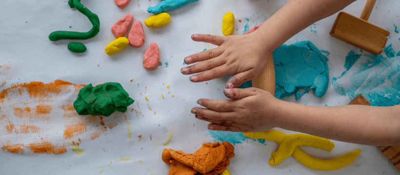 A picture of a child's hands playing with brightly coloured playdough